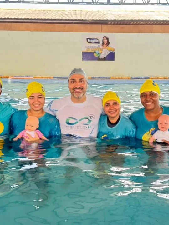 Equipe da Acqua Stilo com alunos e um bebê na piscina