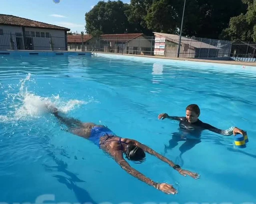 Aluna nadando na piscina acompanhada de perto pelo professor